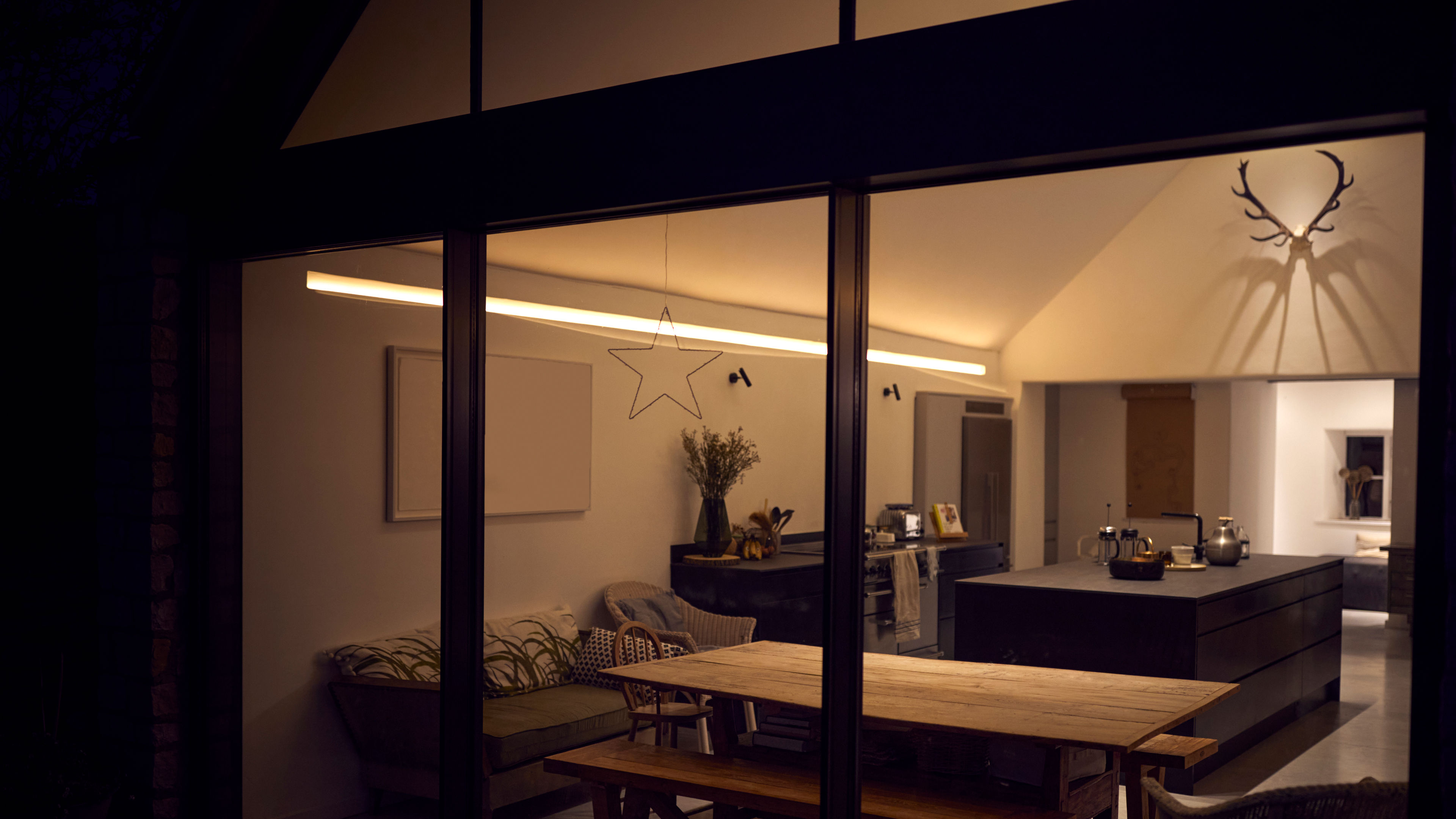 An exterior view of a home with lights on, showing visible appliances and a warm, welcoming interior.