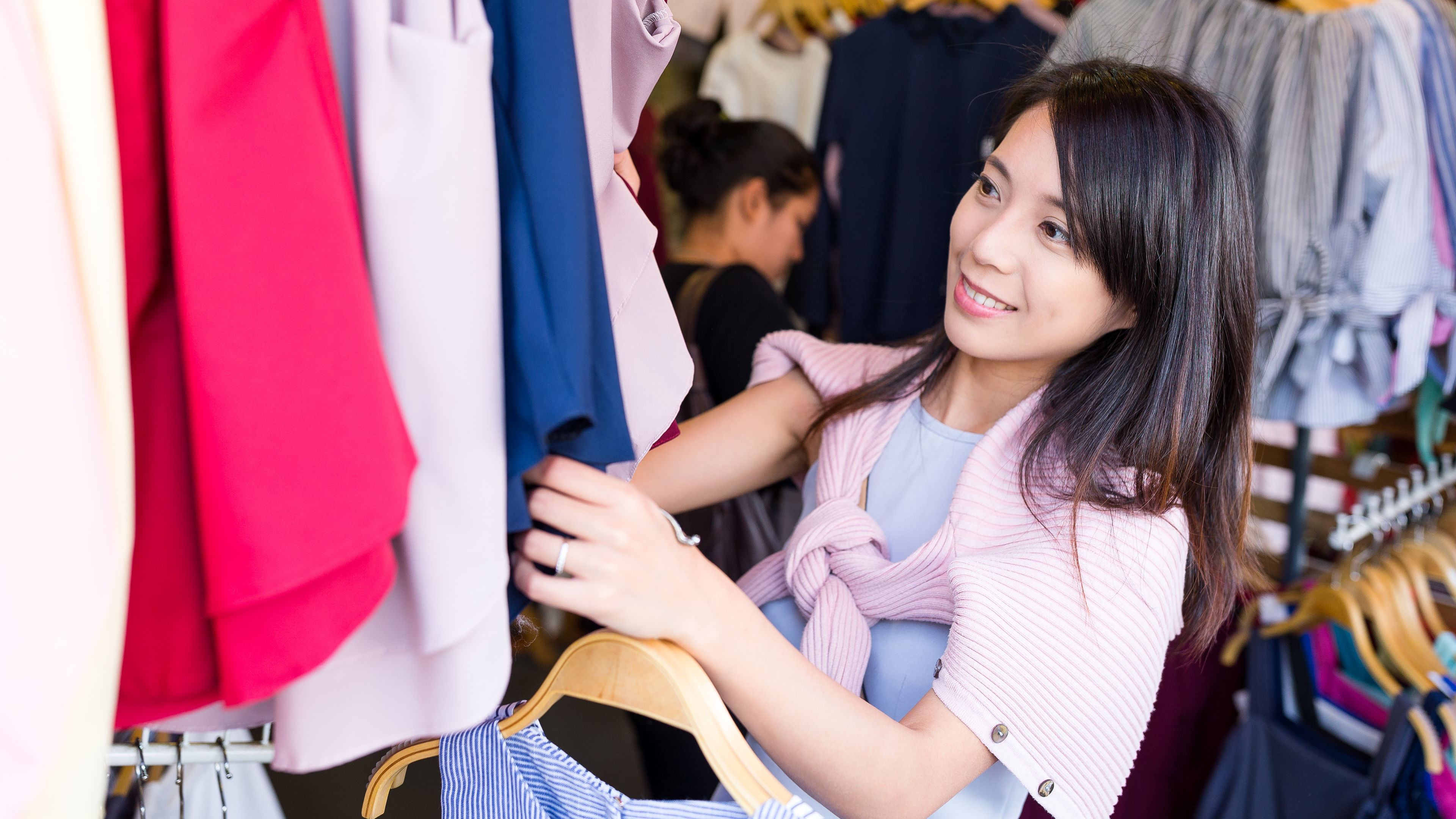 Women select dresses from a store with a wide variety to choose from.