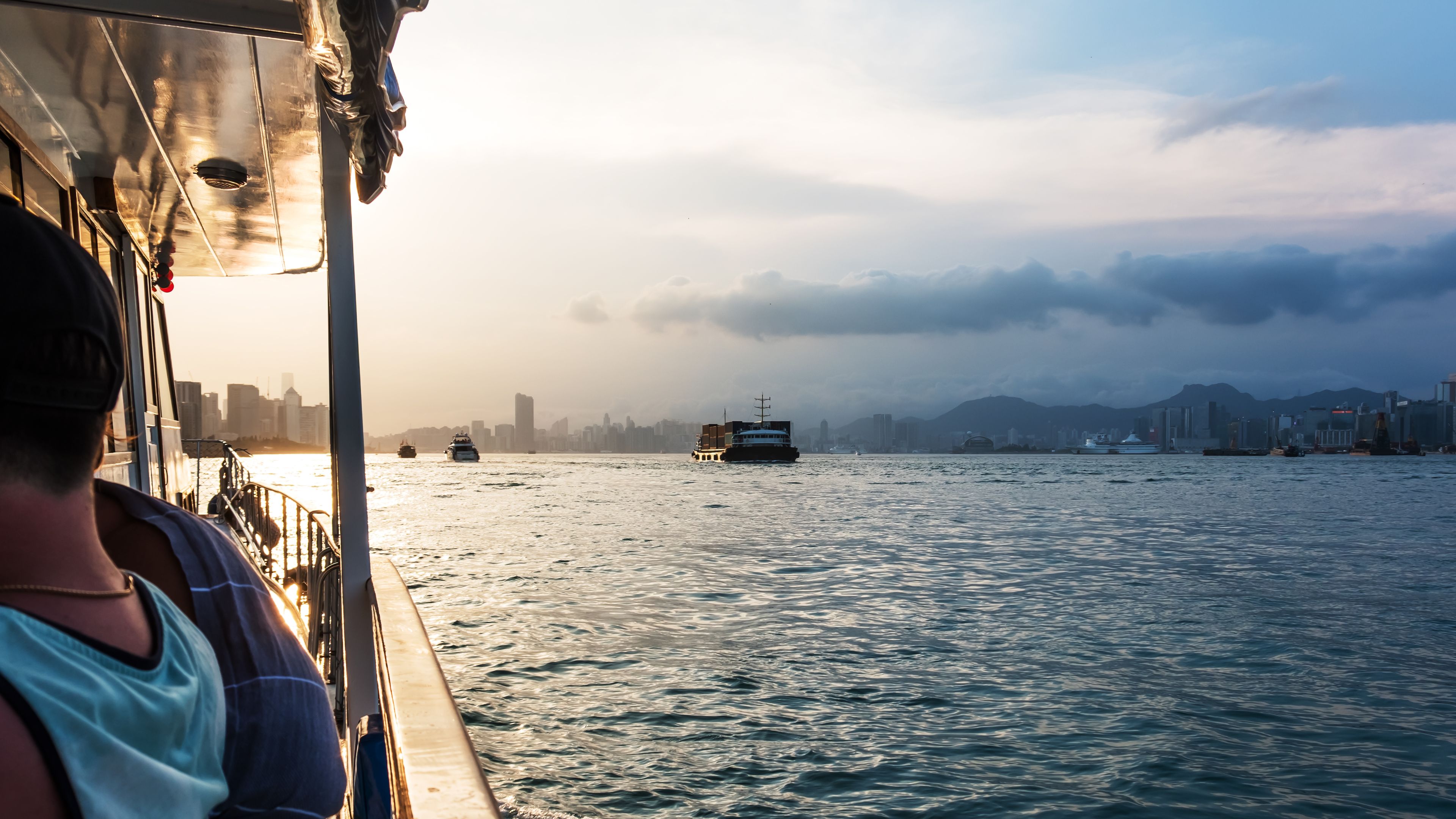 Pleasure boat moving across Victoria harbour at sunset.