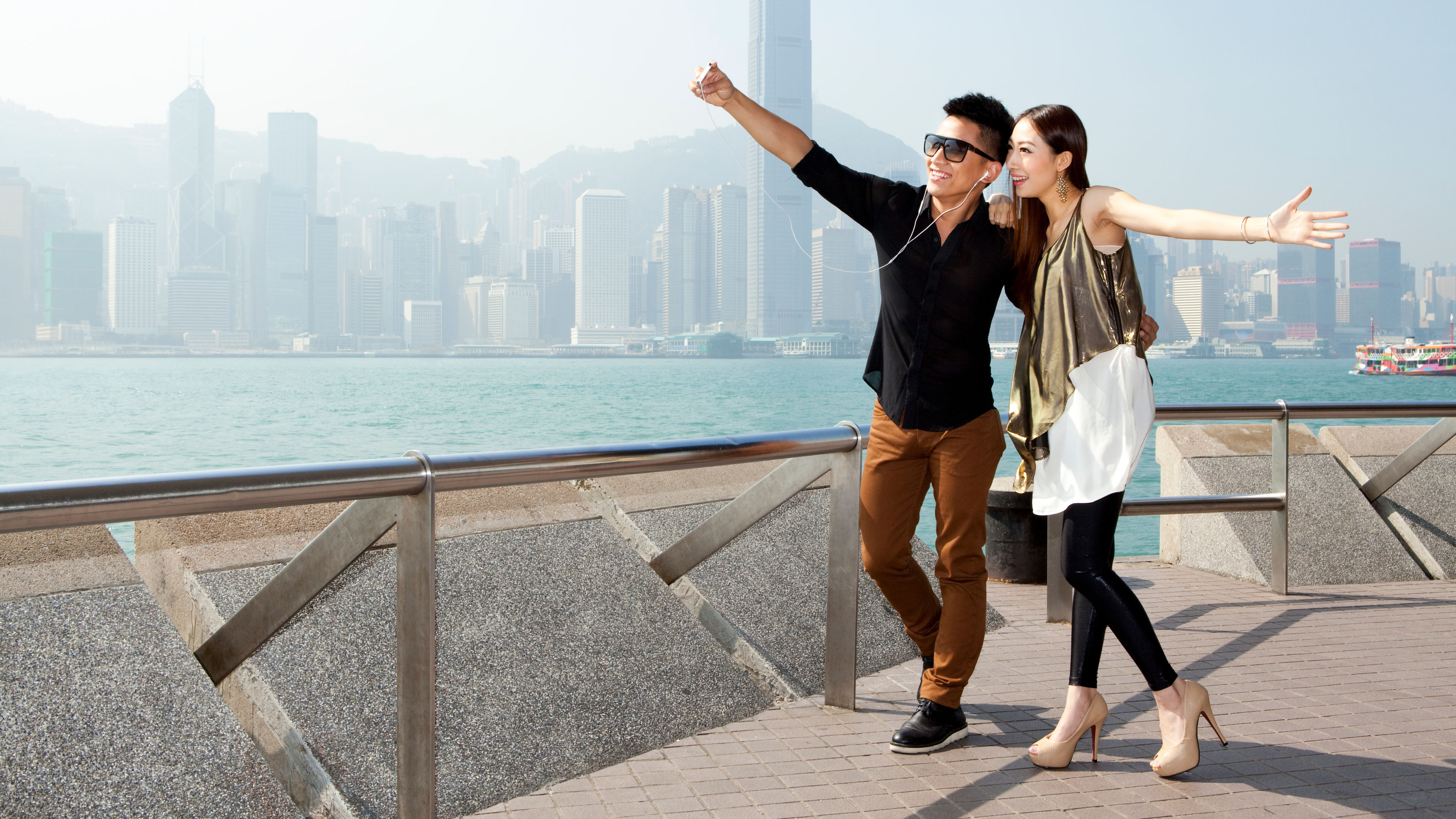 Fashionable young Chinese couple taking self-portrait pictures with smart phone 