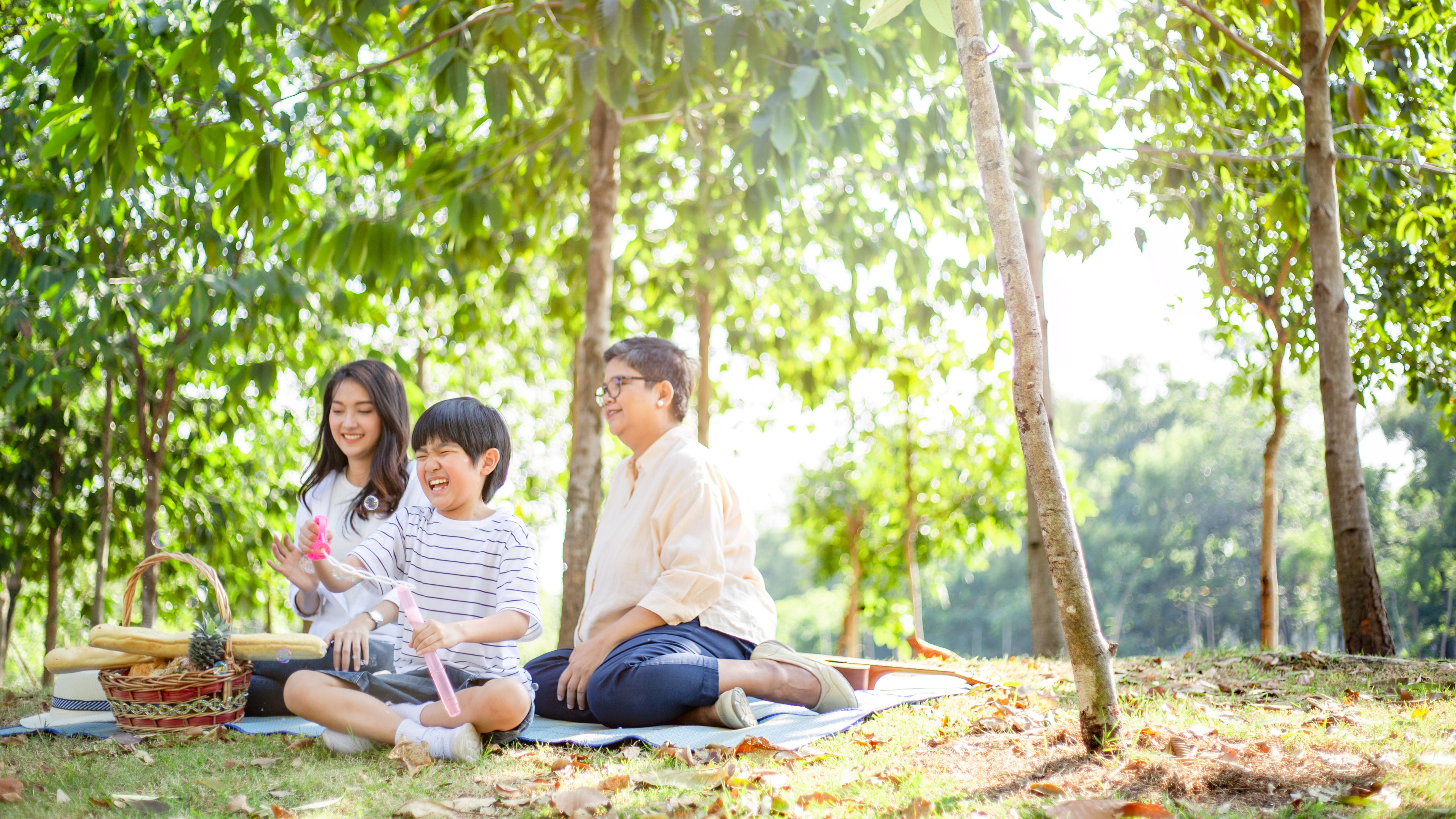 In a serene park, a smiling family sits on a blanket, sharing laughter and snacks 