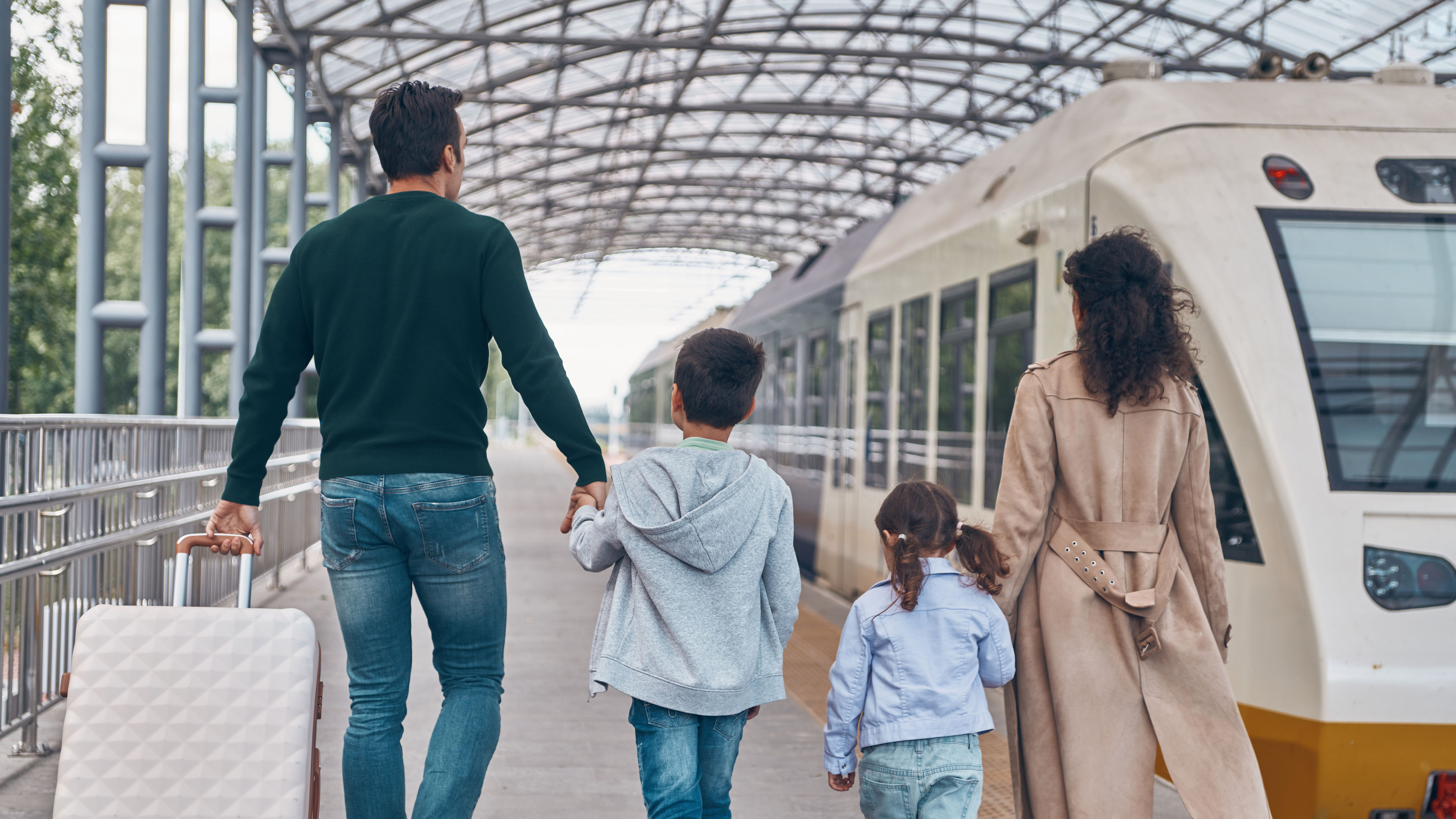 A family of four walks along a train platform.