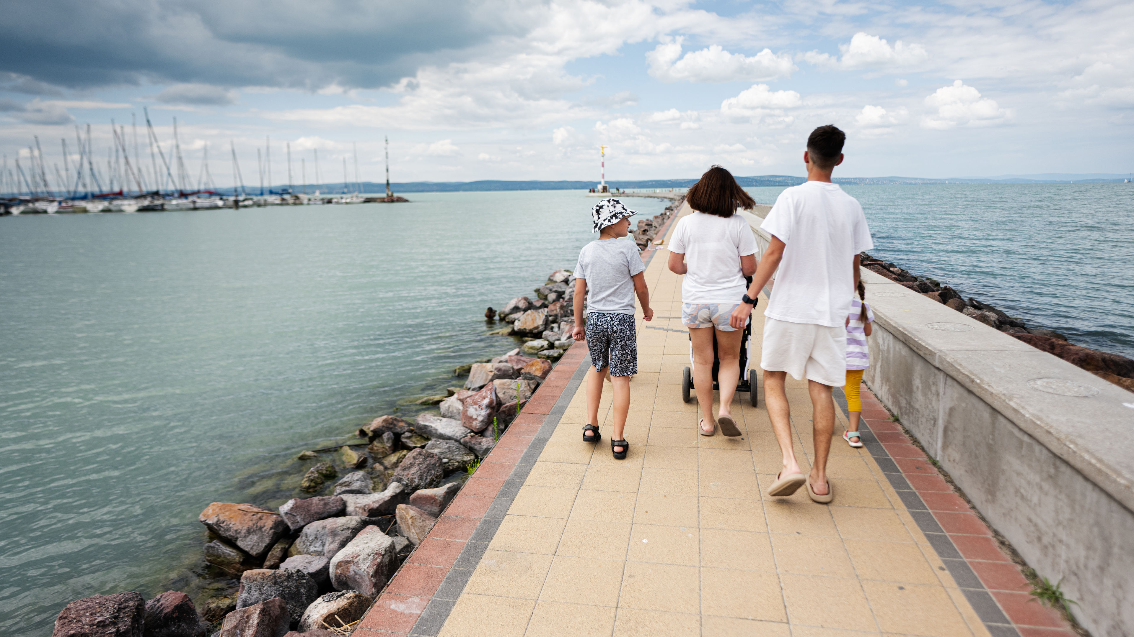 A family of four walking on a bridge by watching the scenery. 