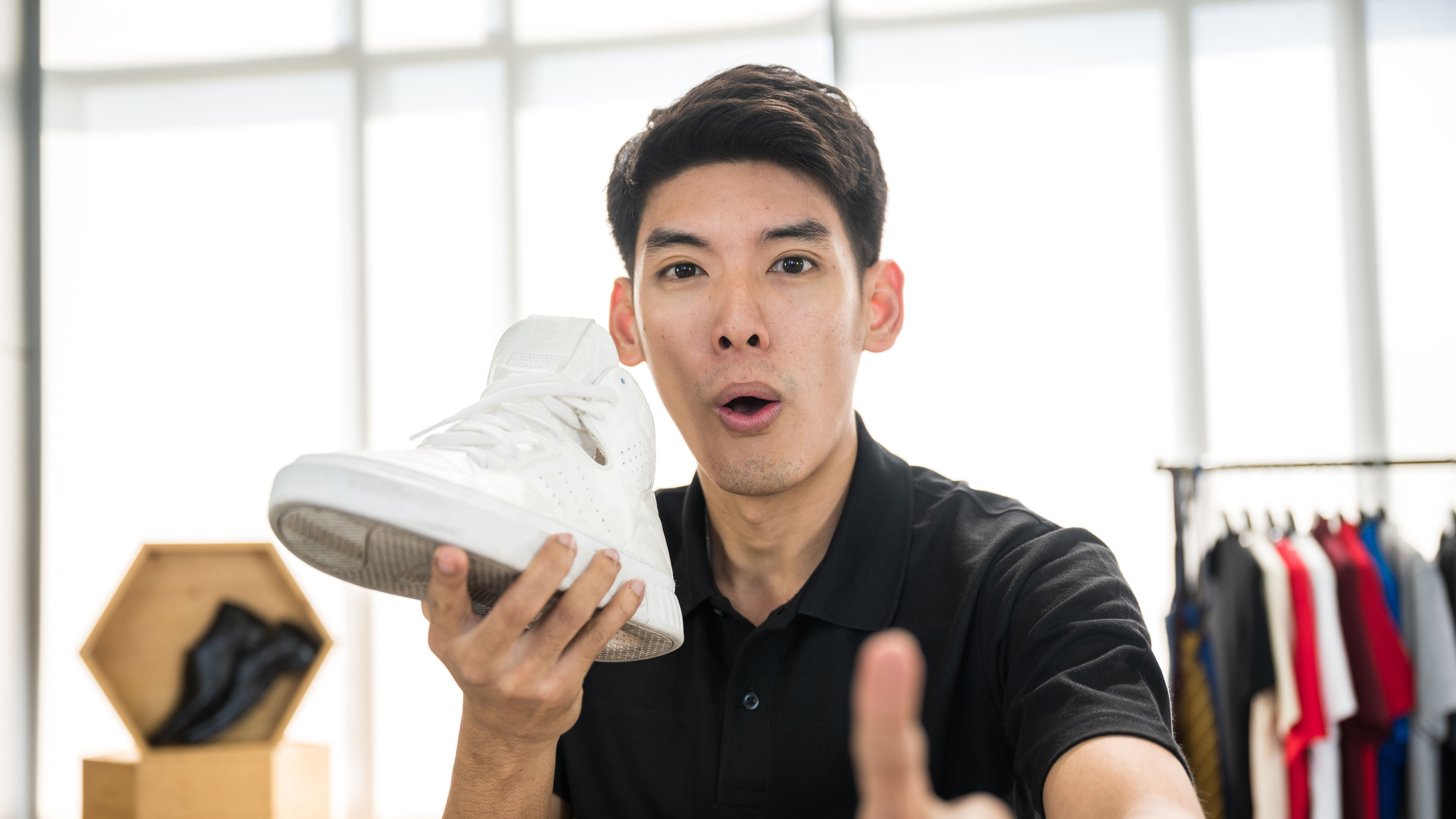 A man is looking at the camera with an excited face with a white shoe in hand.