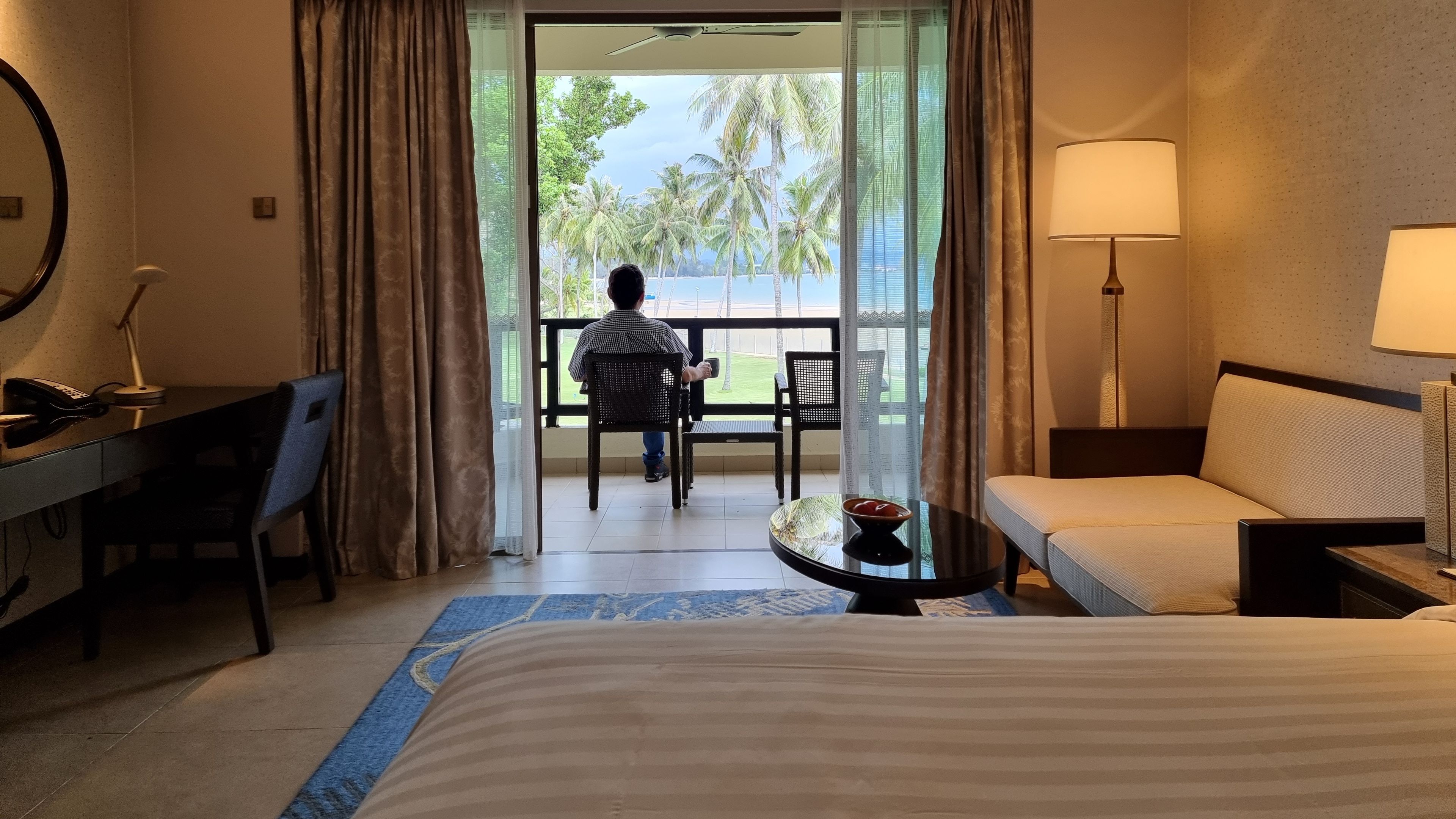 A man sitting in a balcony of a hotel room 