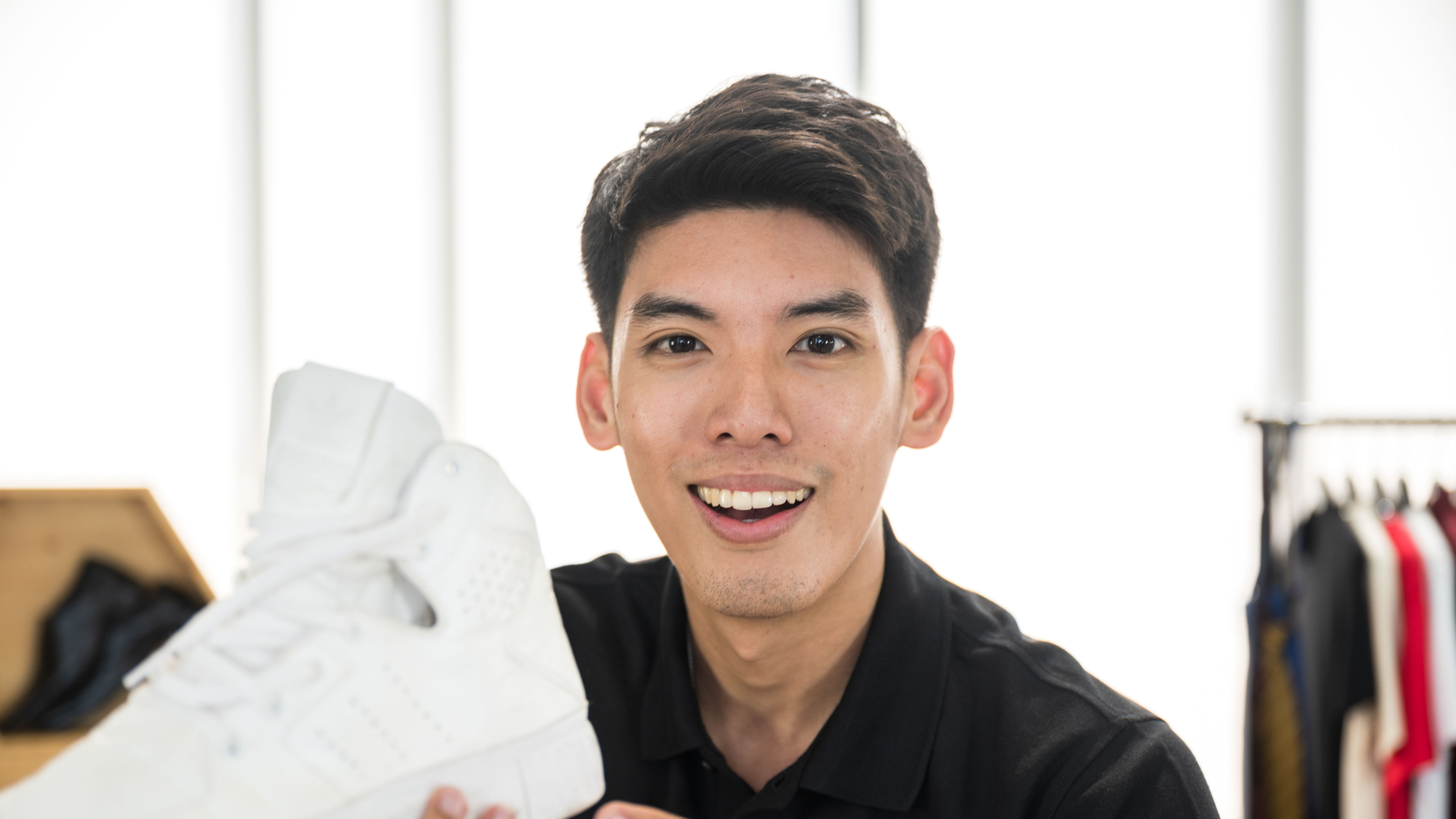 A man enthusiastically shows off a white sneaker 