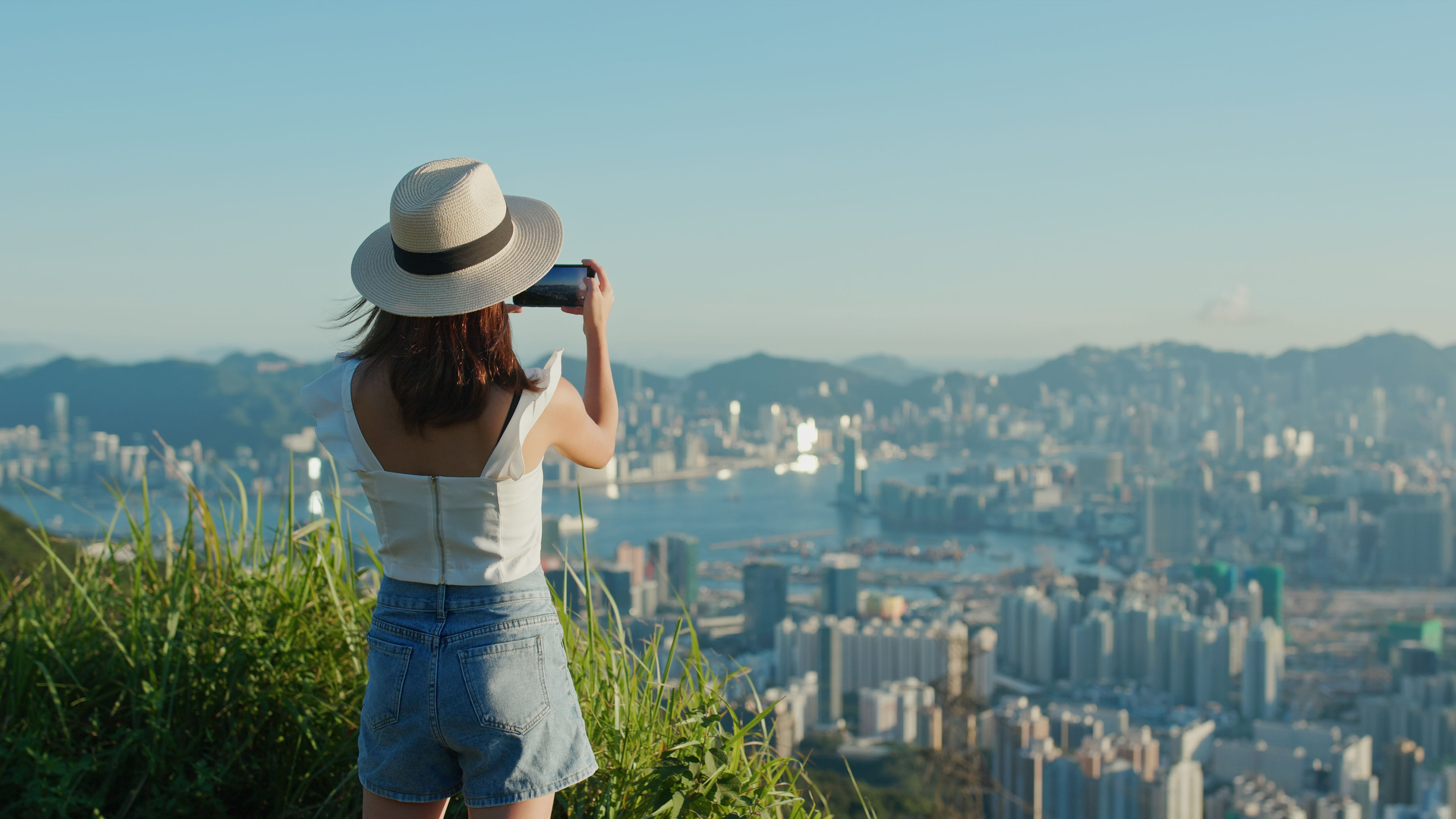 A woman is taking a picture of the sunset from the top. 