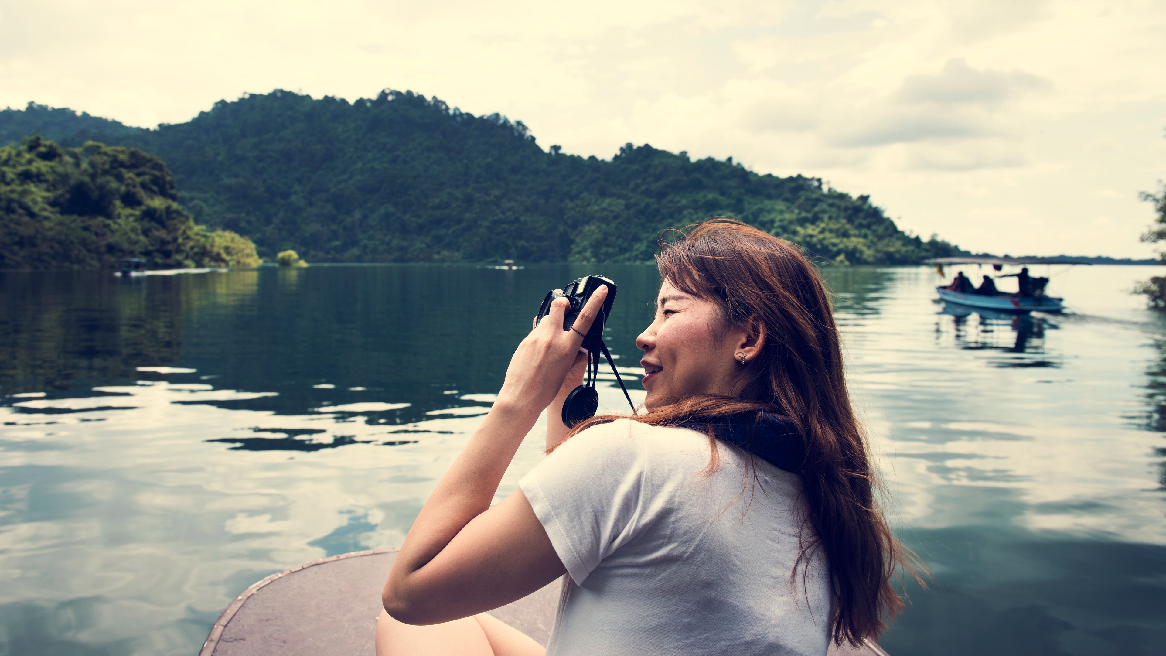 A woman enjoying taking pictures by travelling on a boat. 