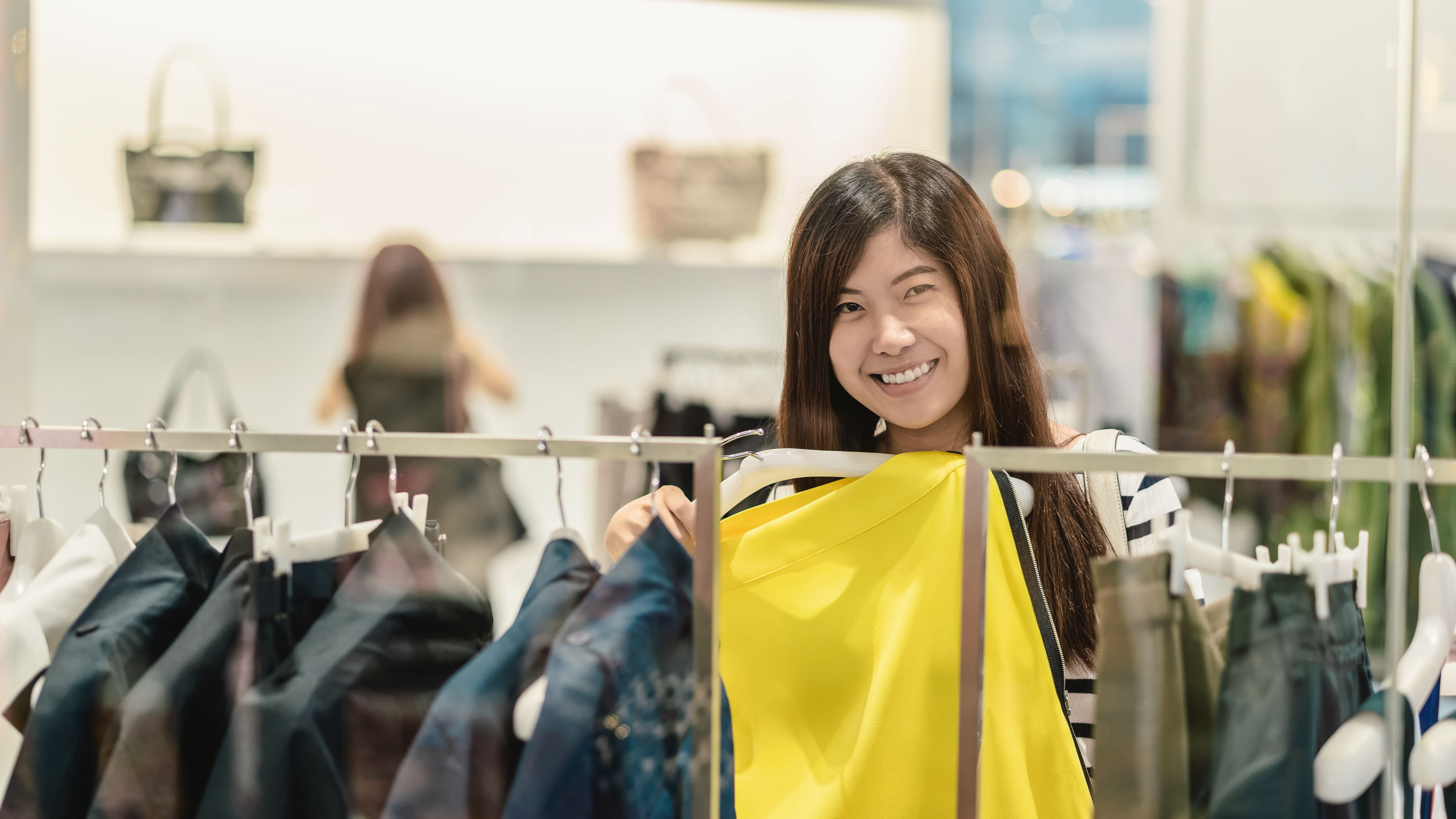 A woman happily trying new clothes in a store 