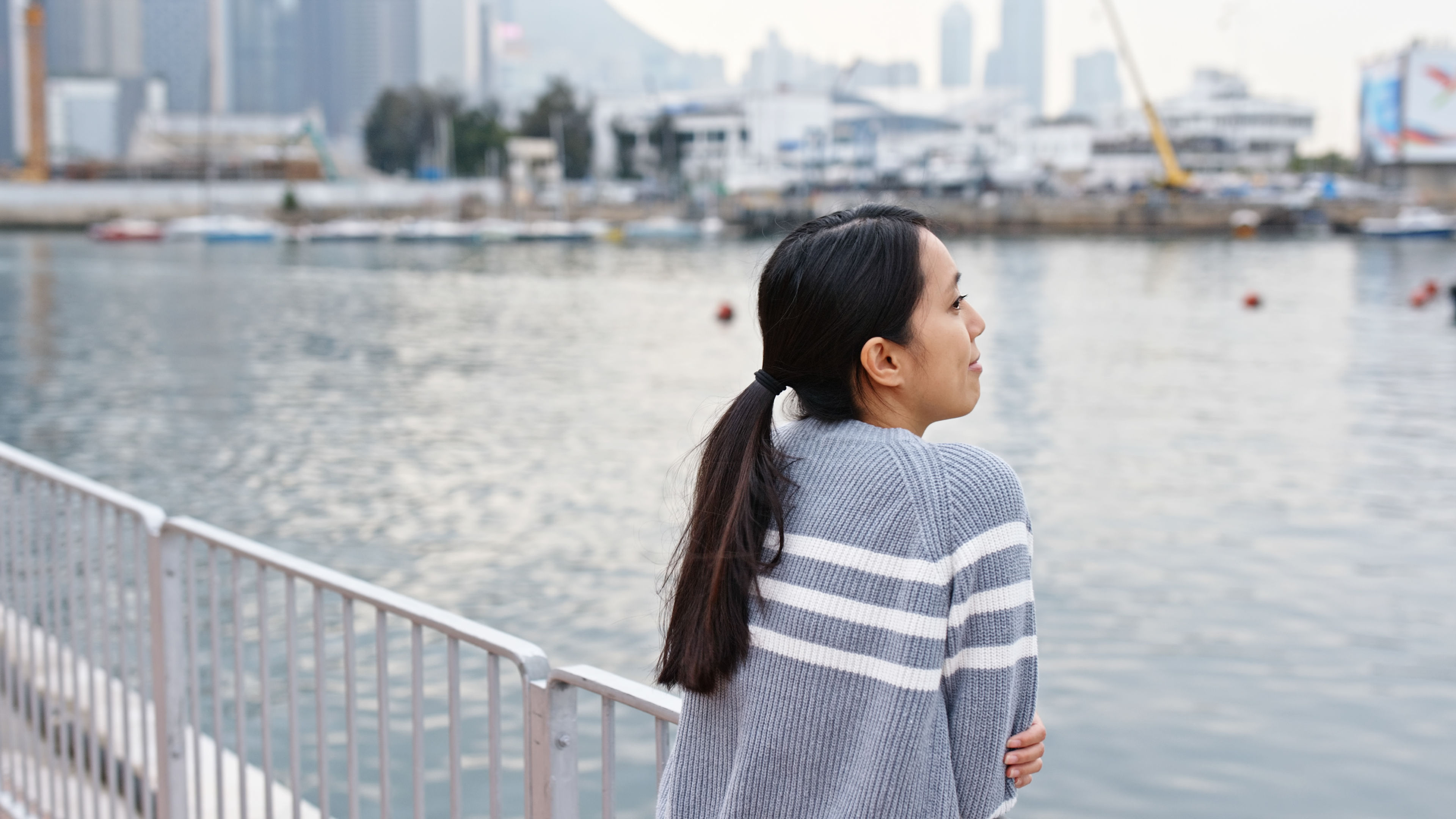 A woman wears stylish clothing and looking at the sea 