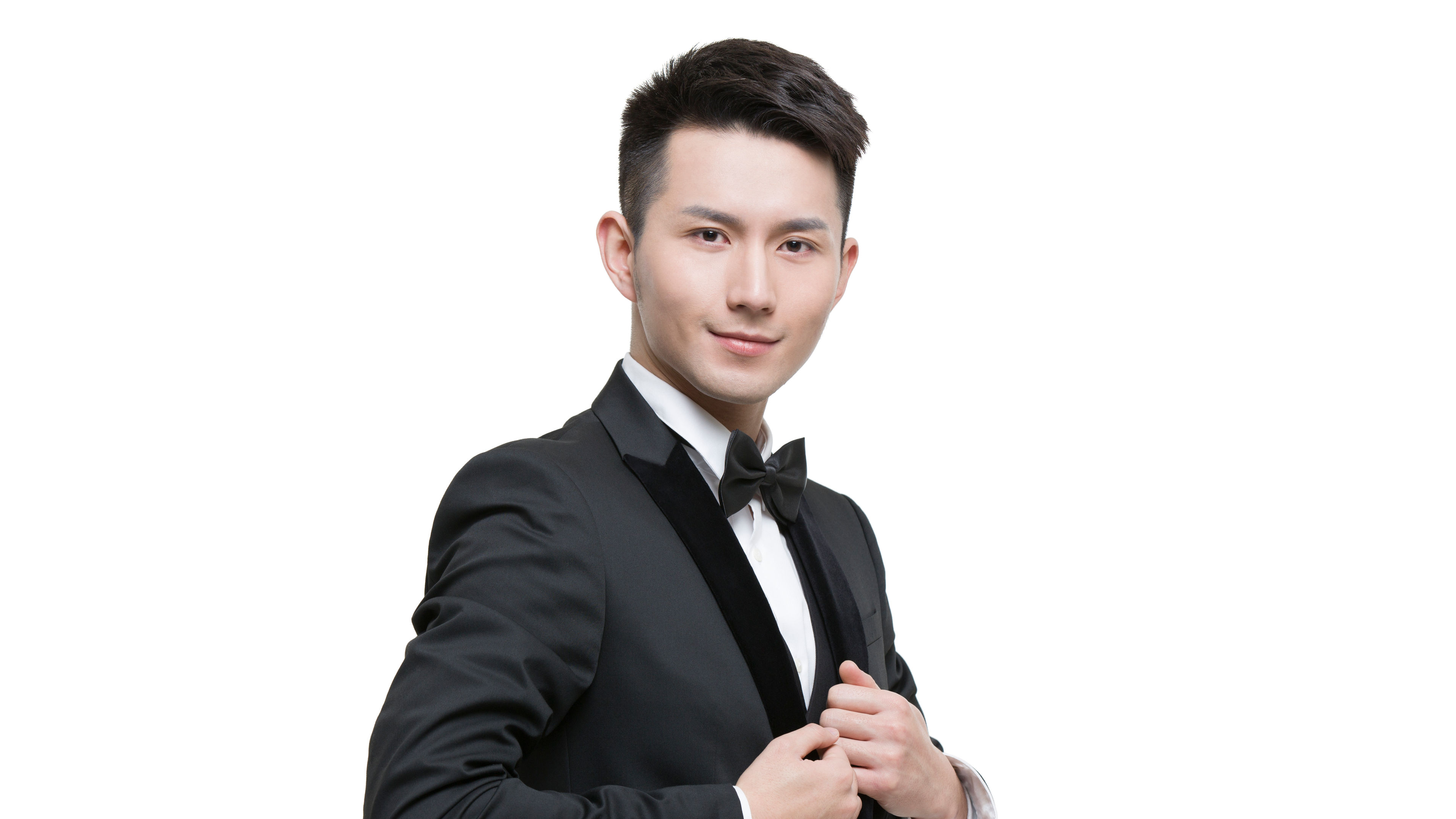 A young man confidently adjusts his tuxedo jacket 