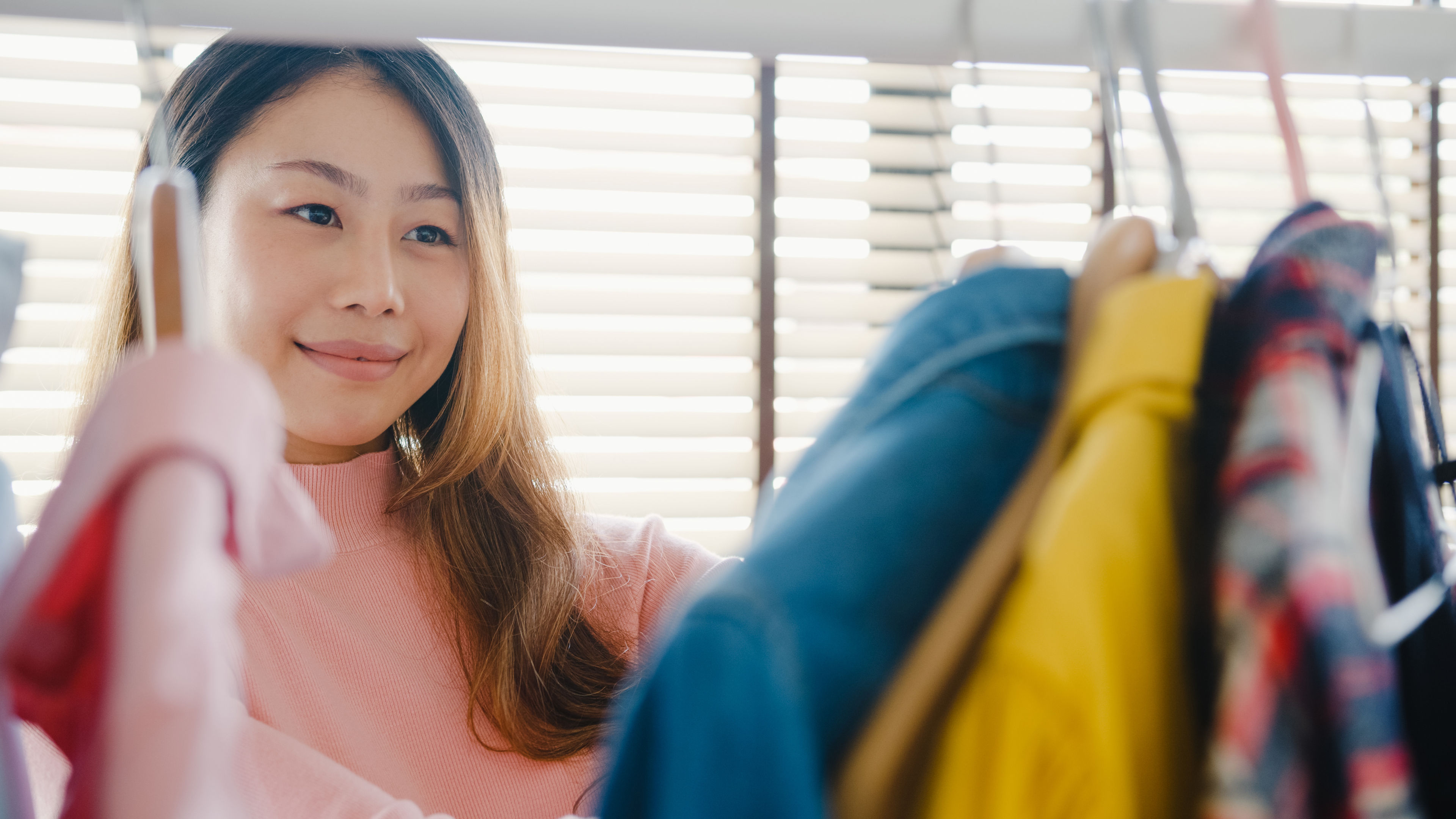 Beautiful attractive young lady choosing her fashion outfit clothes in closet at house.  