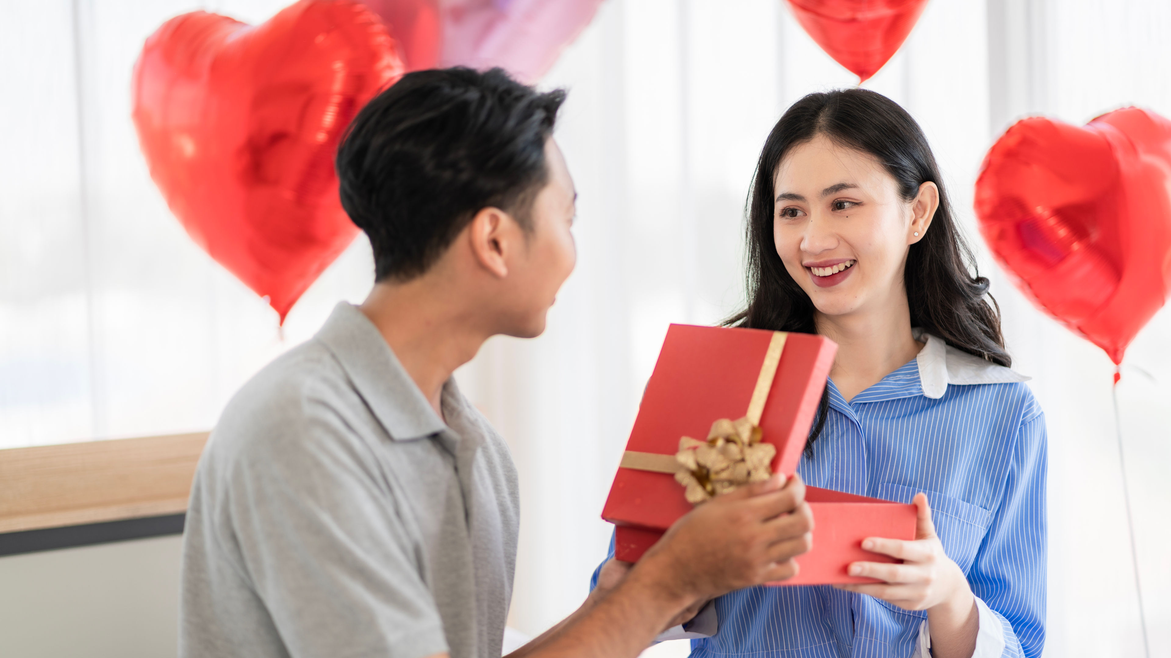 Asian couples Show love by surprising each other with flowers or gifts on important occasions such as Valentine's Day, birthdays, or wedding anniversaries. They do this with love and warmth in the bedroom of their home. 