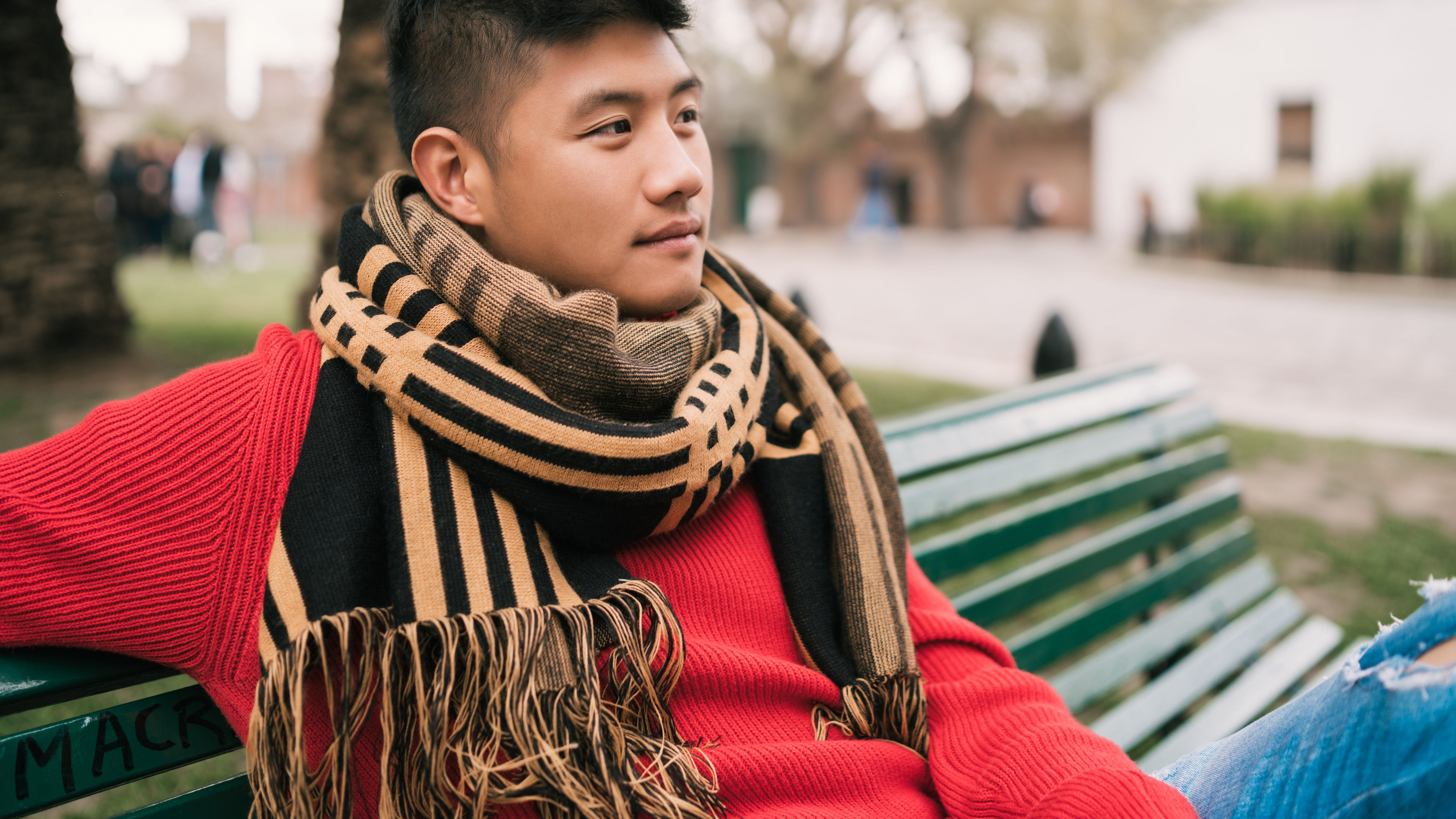 Image of an asian man sitting on a bench 
