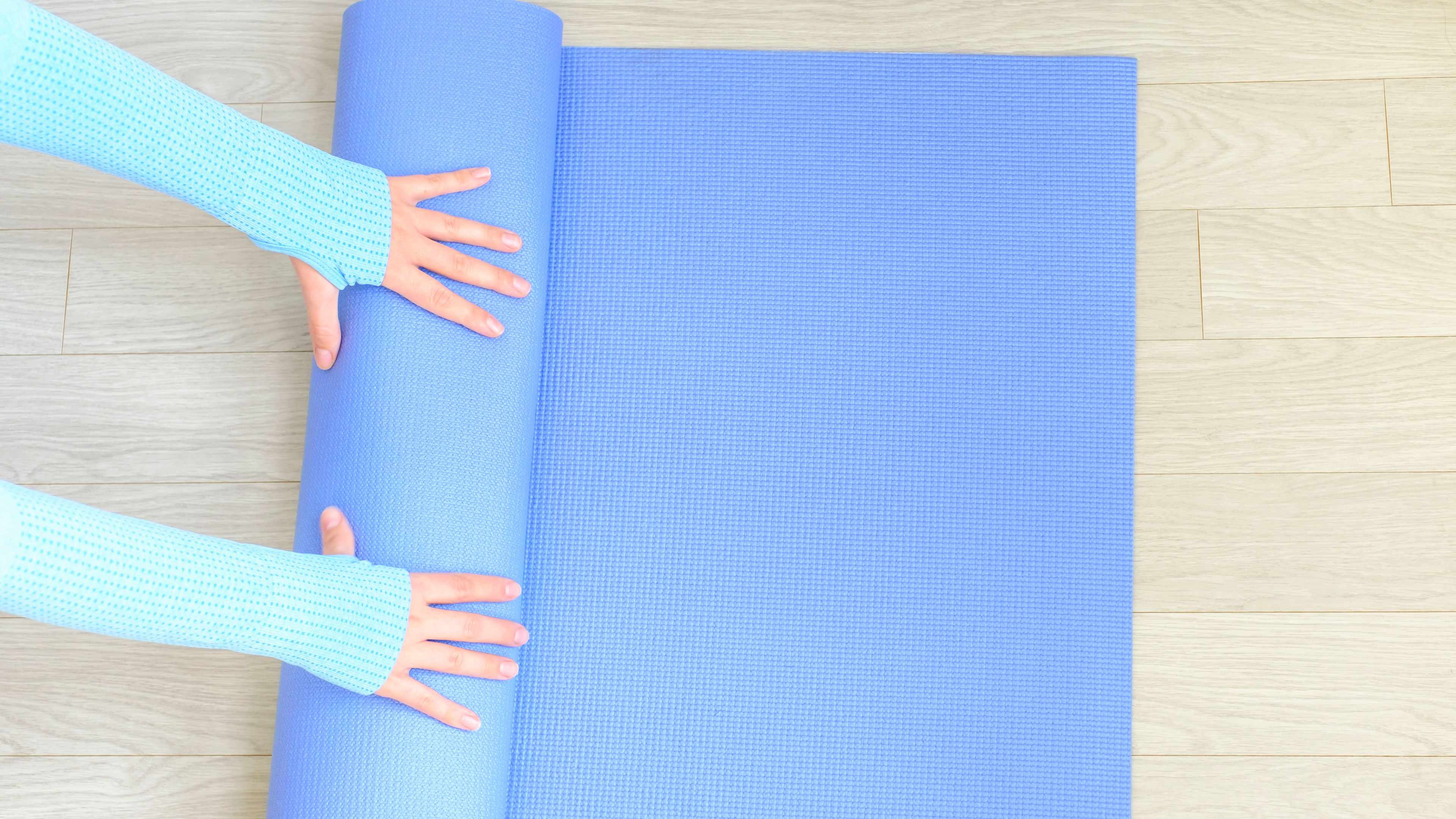 Image of female hands rolling a mat 