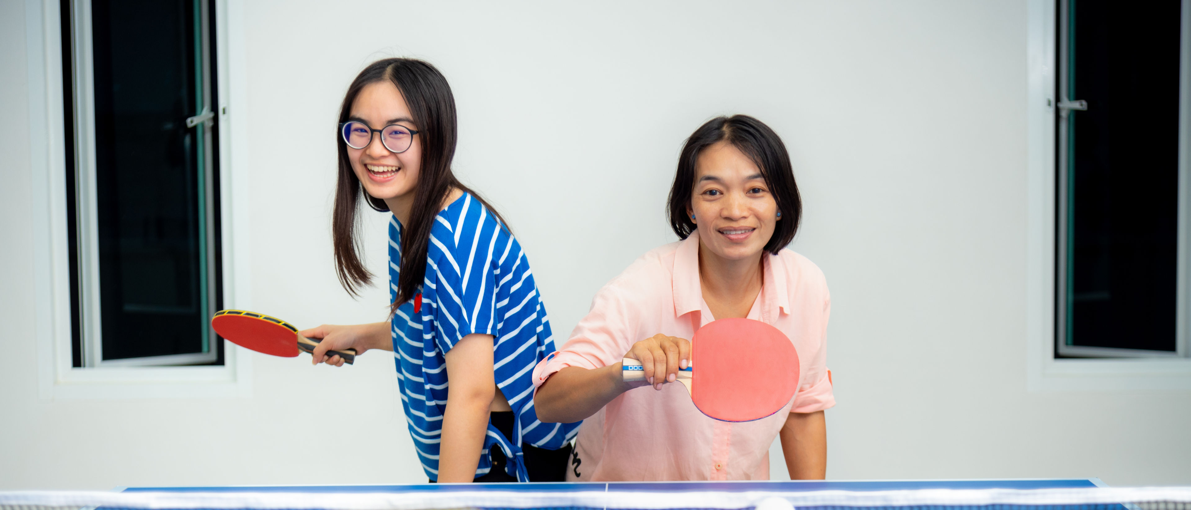 The ladies are playing and enjoying table tennis.