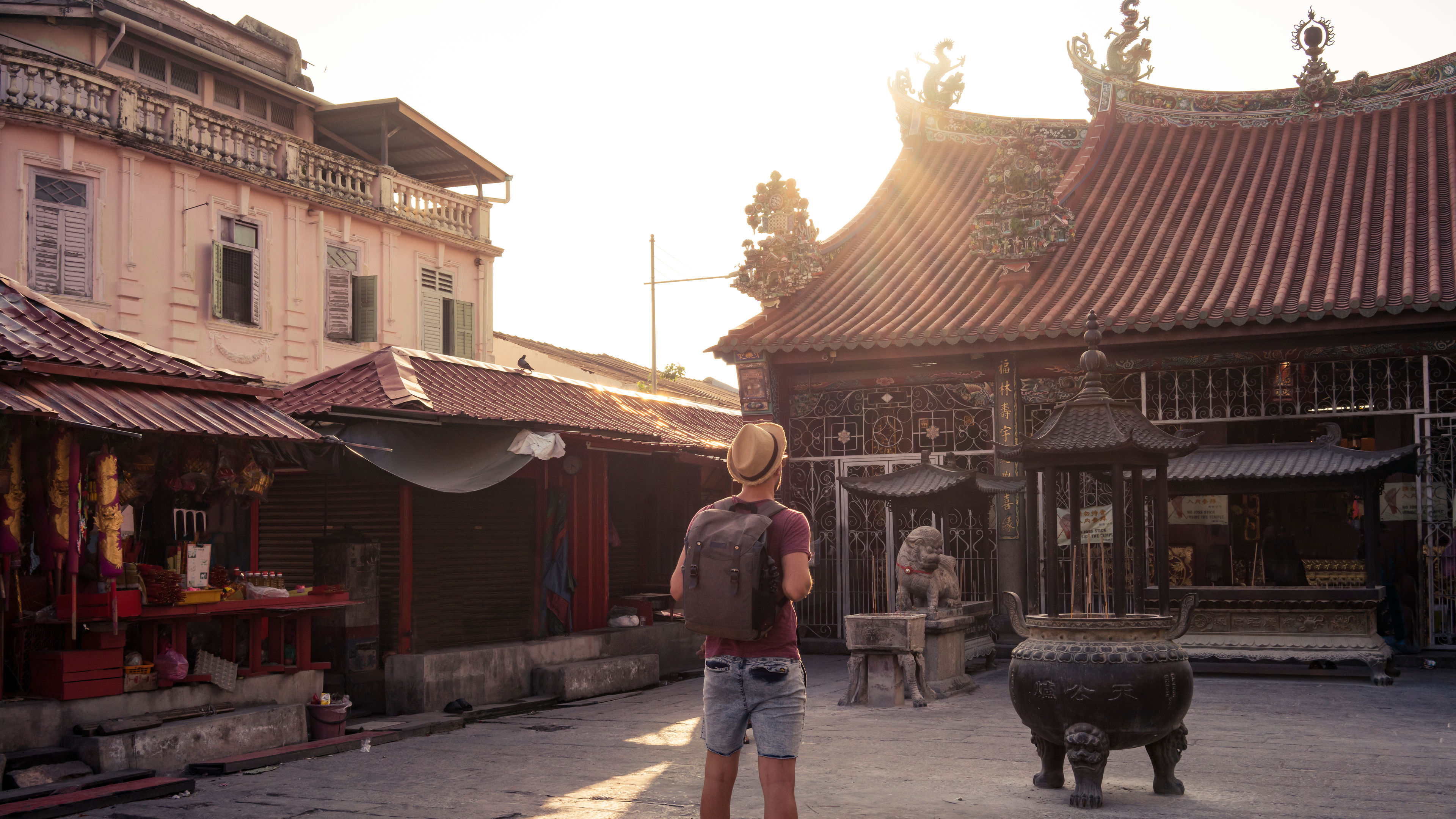 Man with backpack between Asian buildings 