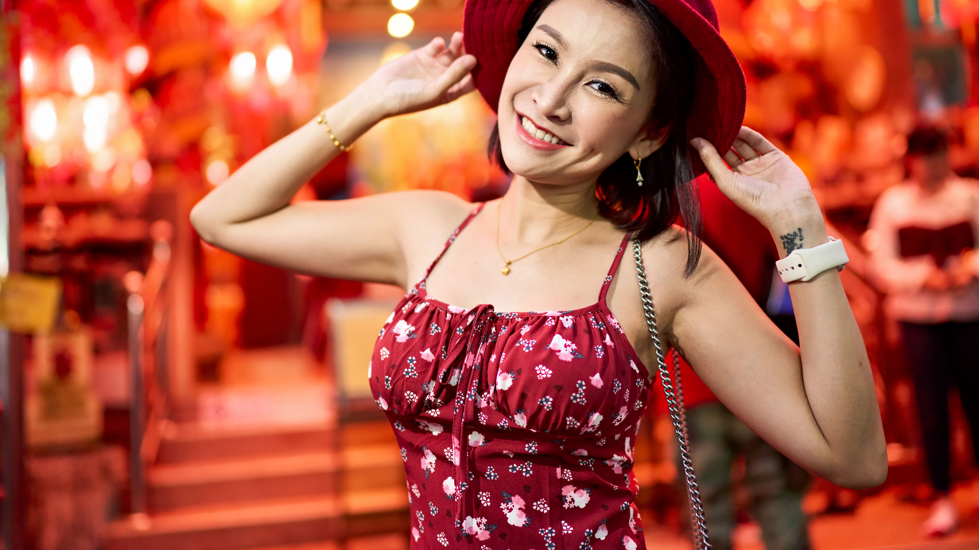 Smiling woman in a red hat and dress, enjoying a festive atmosphere. 