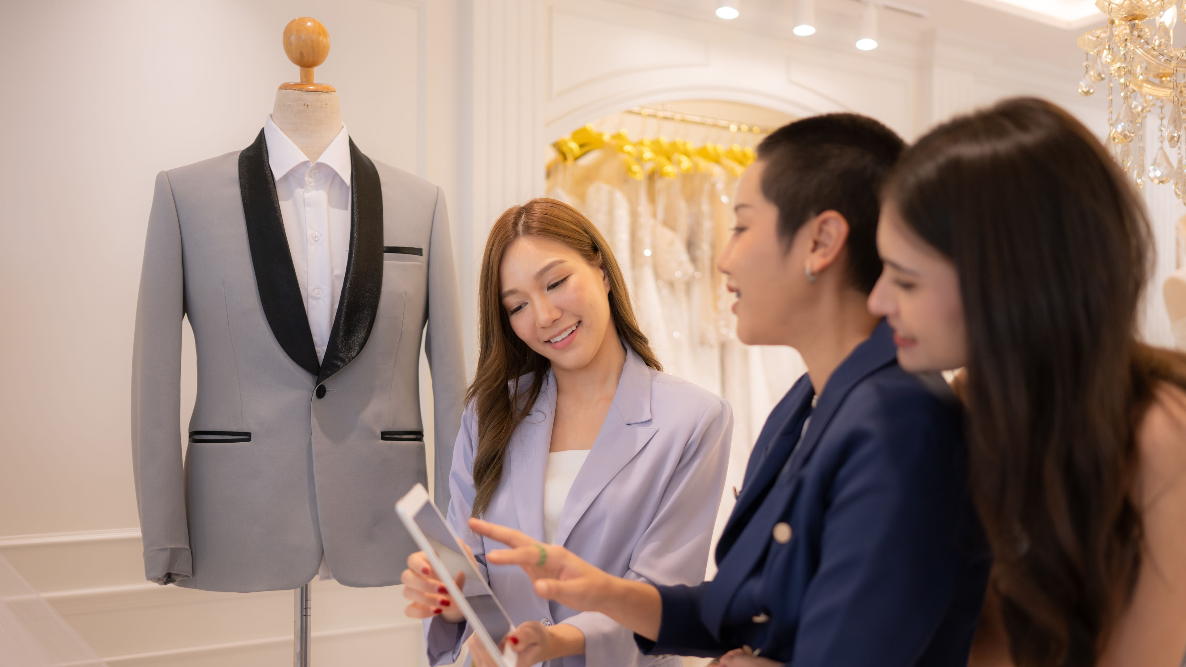 Three women are happily discussing tuxedo options. 