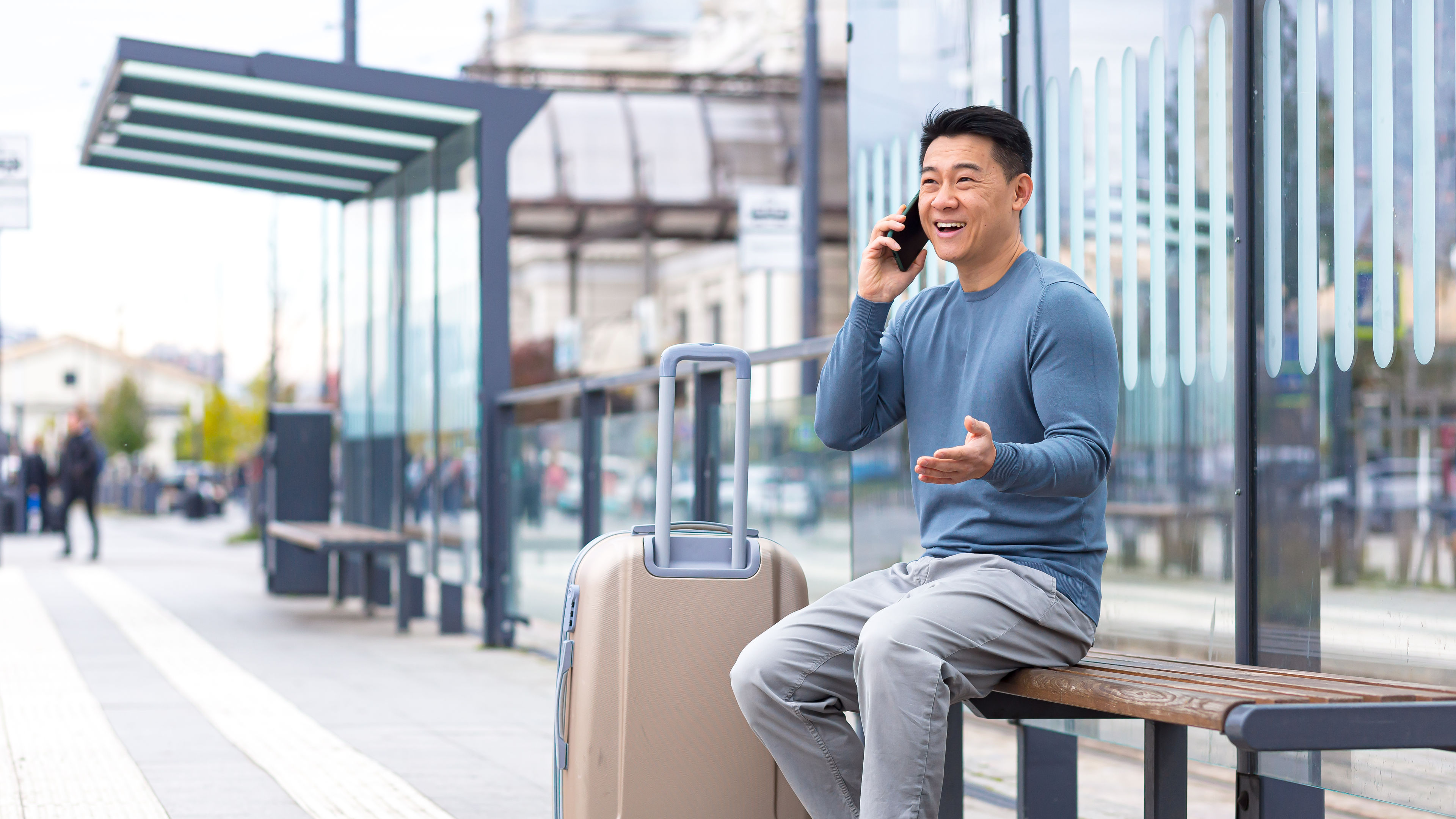 Tourist at the bus station, having fun talking on the phone, sitting on a bench 