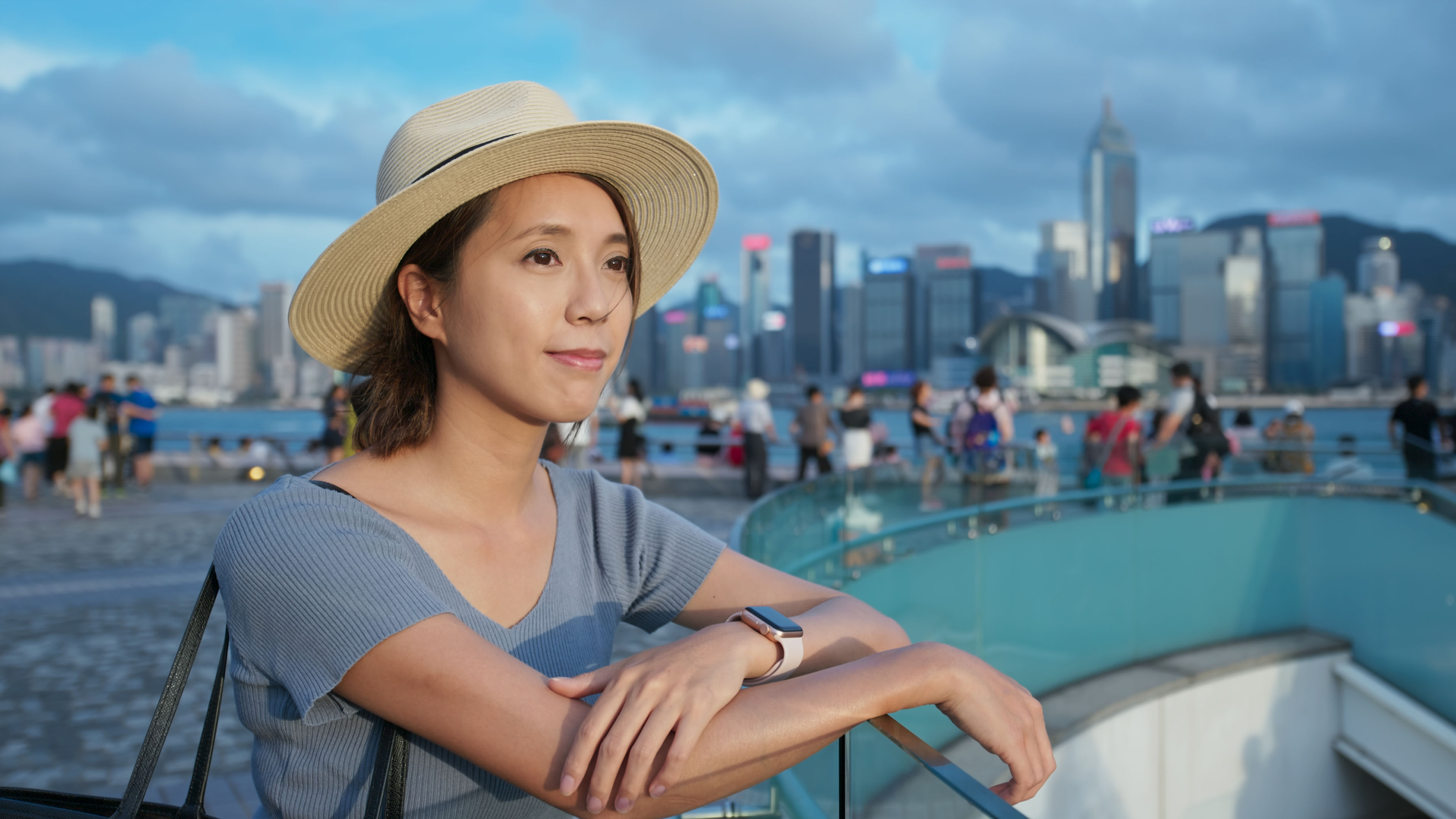 A young woman, dressed in casual yet stylish travel attire, stands on a bustling street in the heart of Hong Kong.  