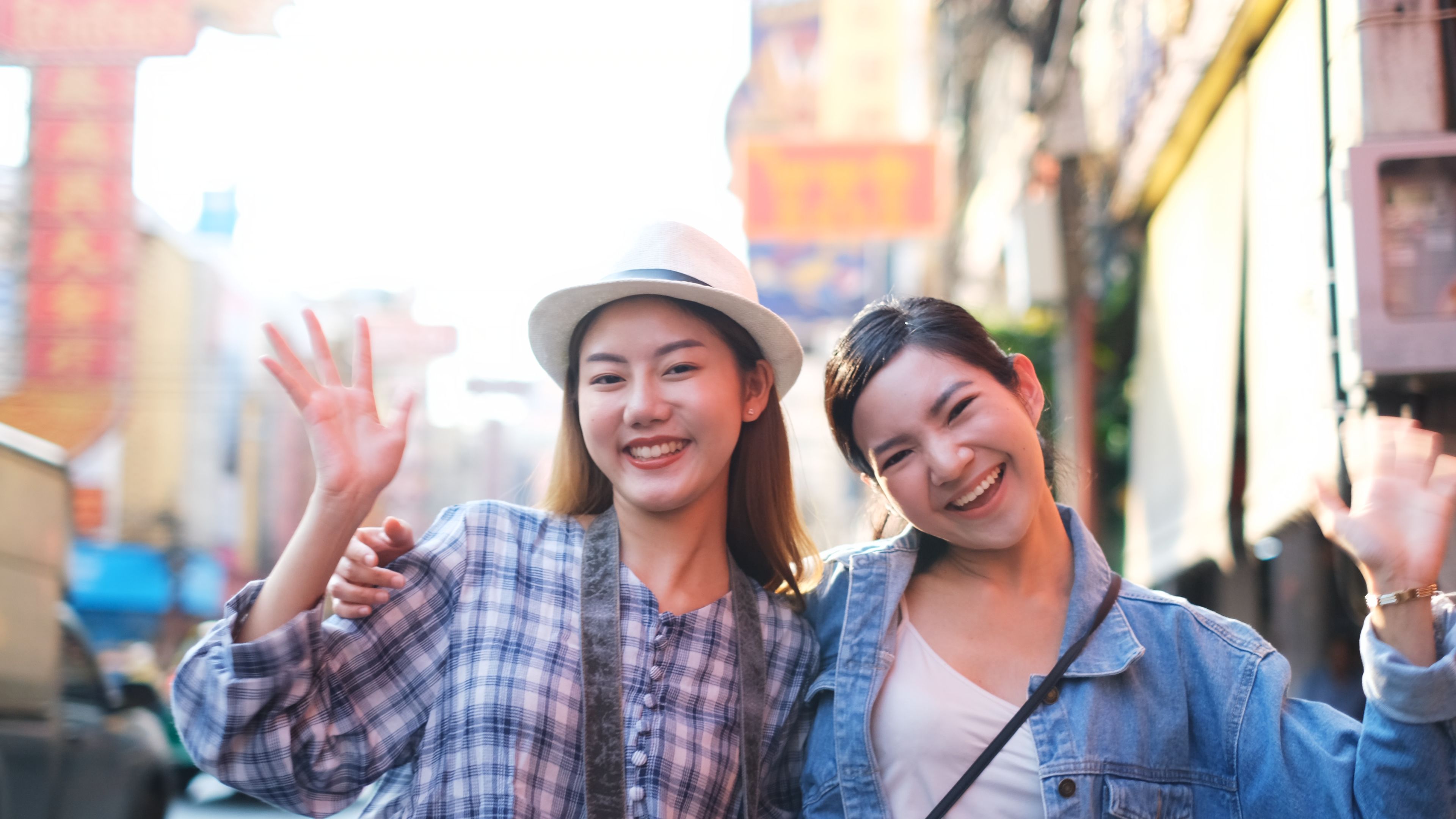 Two cheerful women enjoying a vibrant street scene, radiating joy and travel vibes. 