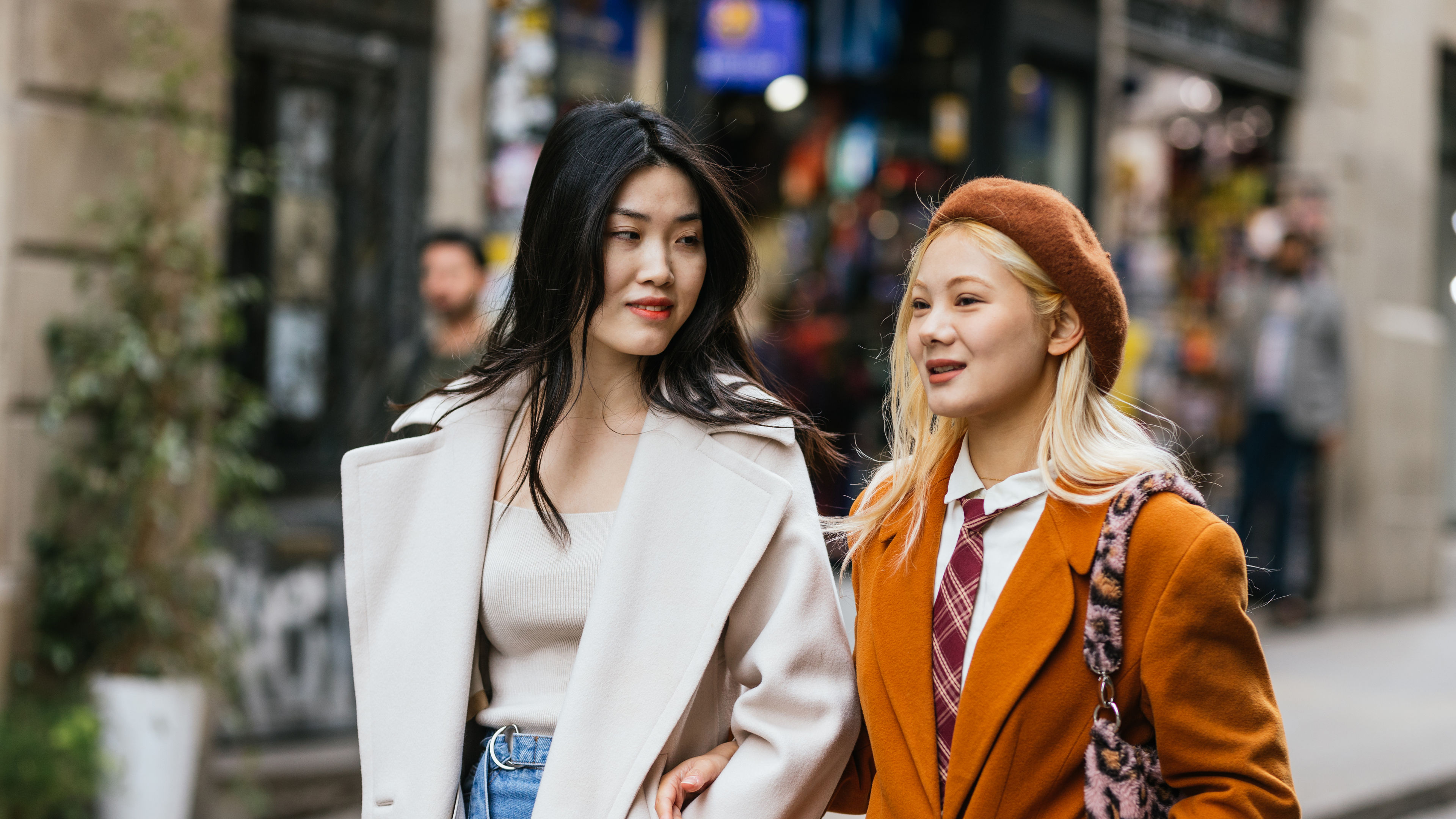 Two stylish young women walking on the street together.