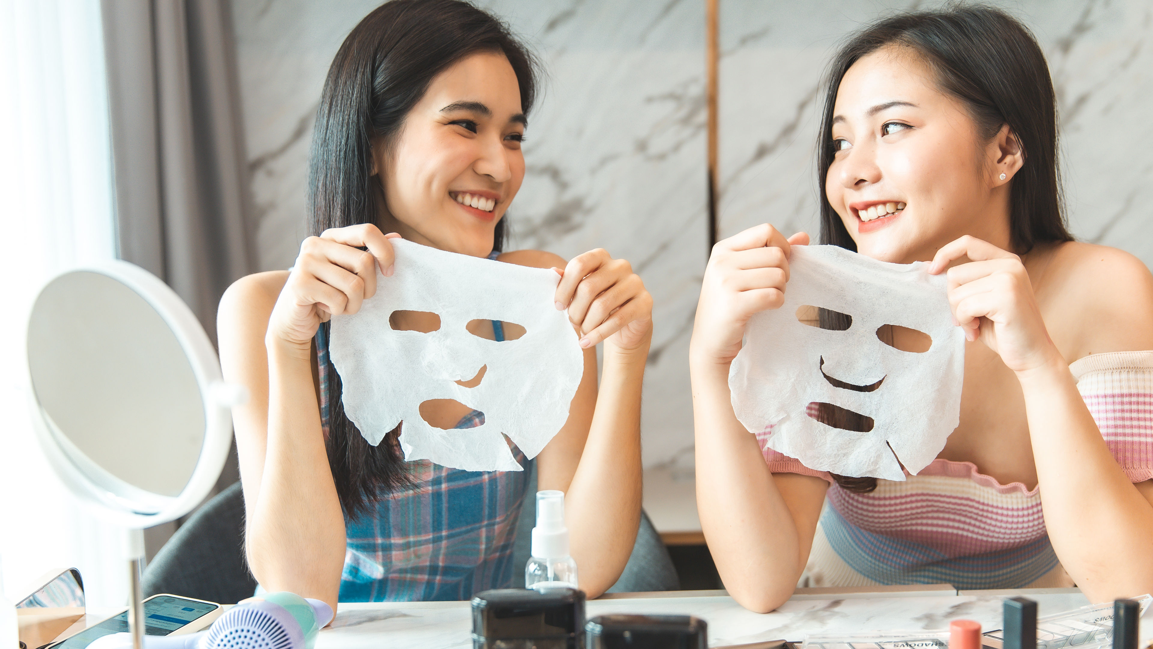 Two women holding face masks in their hands. 