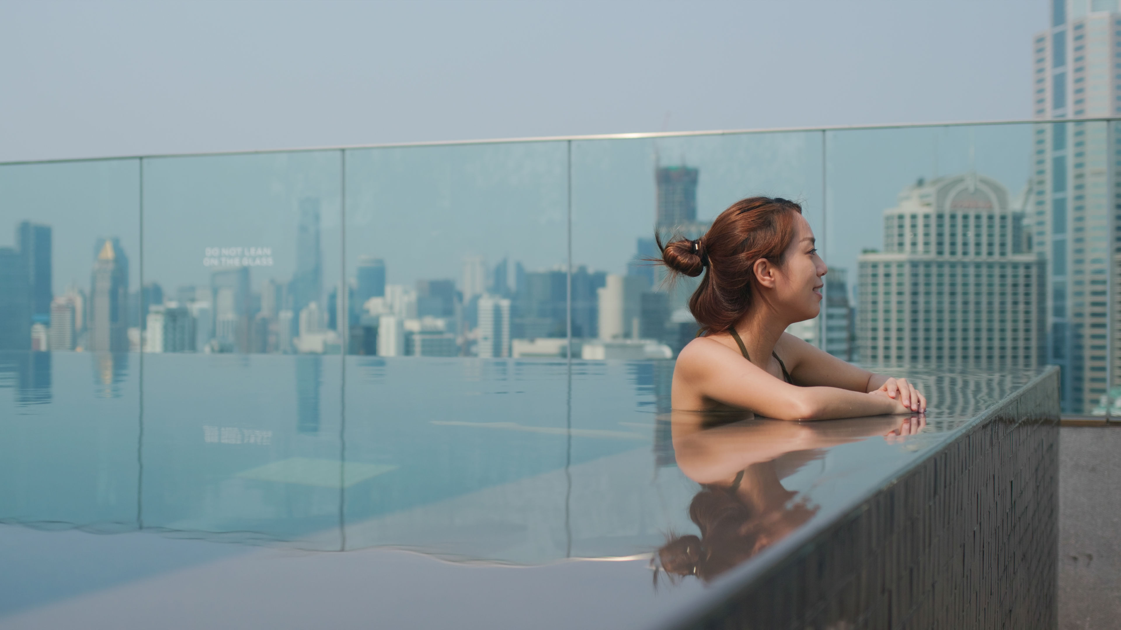 A woman enjoying a peaceful moment by the swimming pool, surrounded by a calm and inviting atmosphere. 