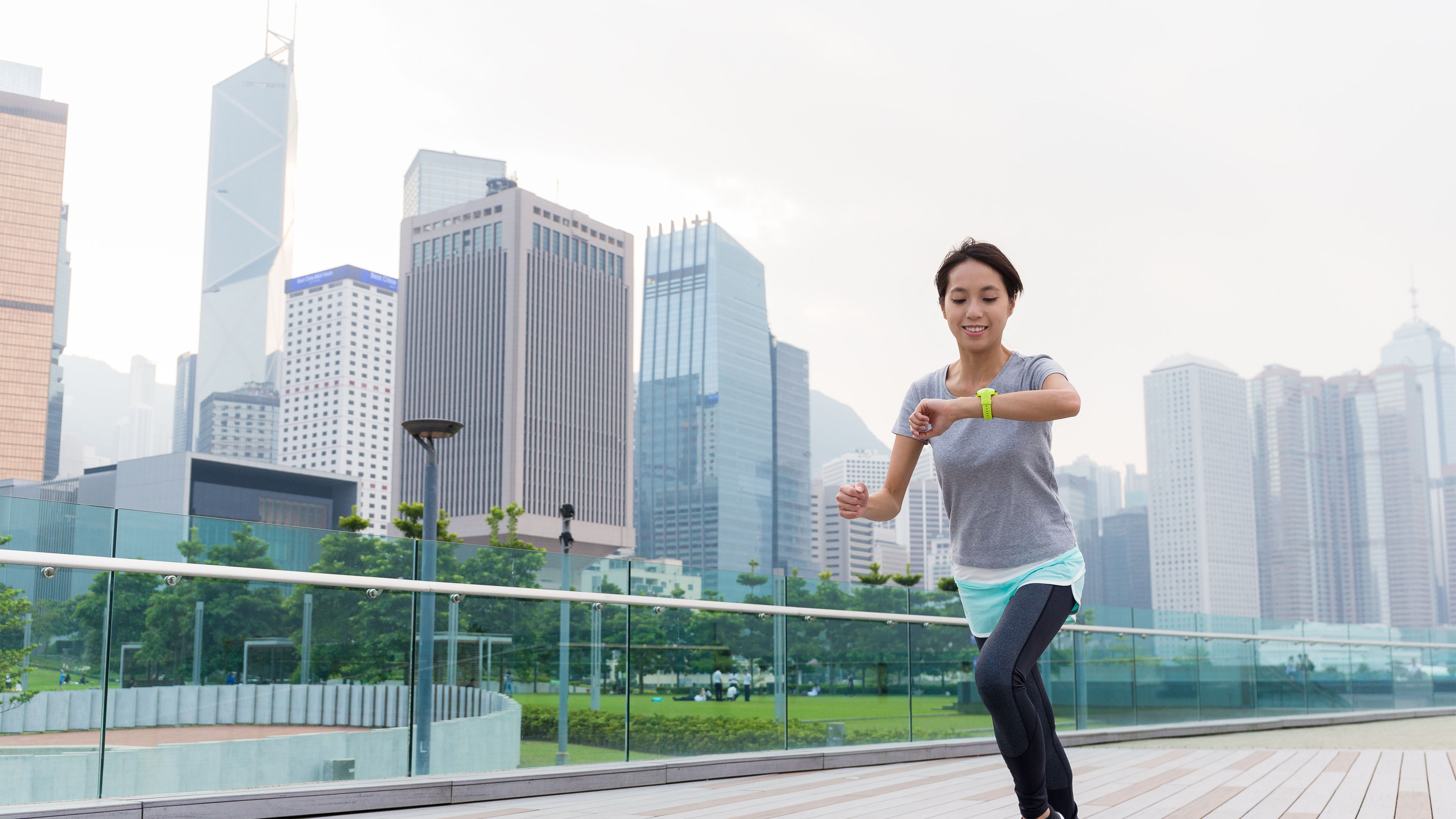 Woman looking at watch and running in joggers