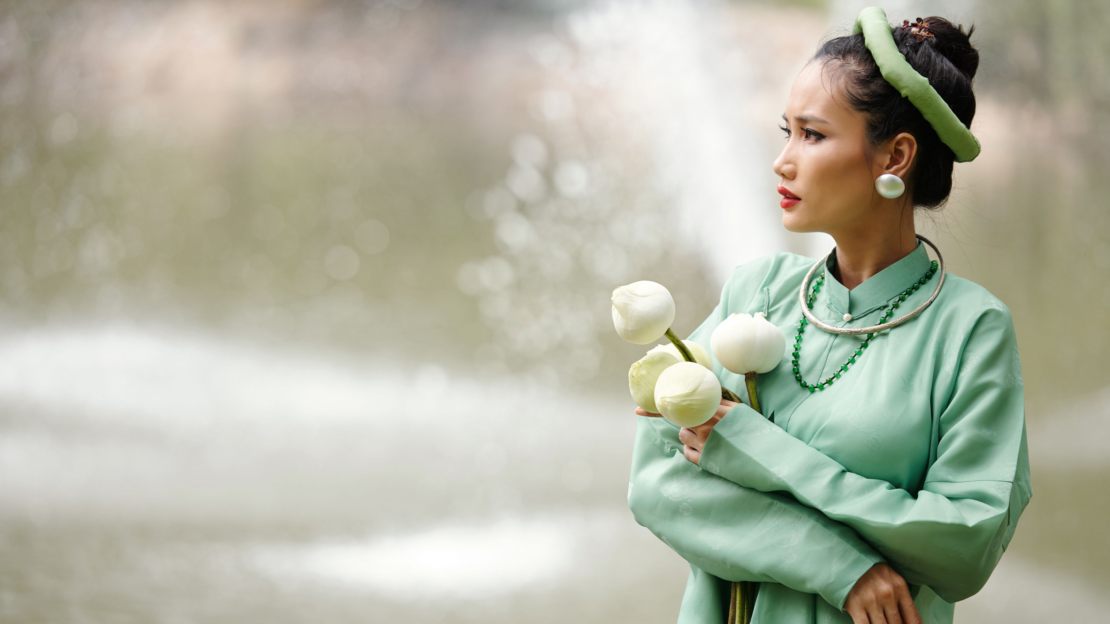 A woman standing near the water, looking concerned and deep in thought, as if pondering a solution or reflecting on something important. 