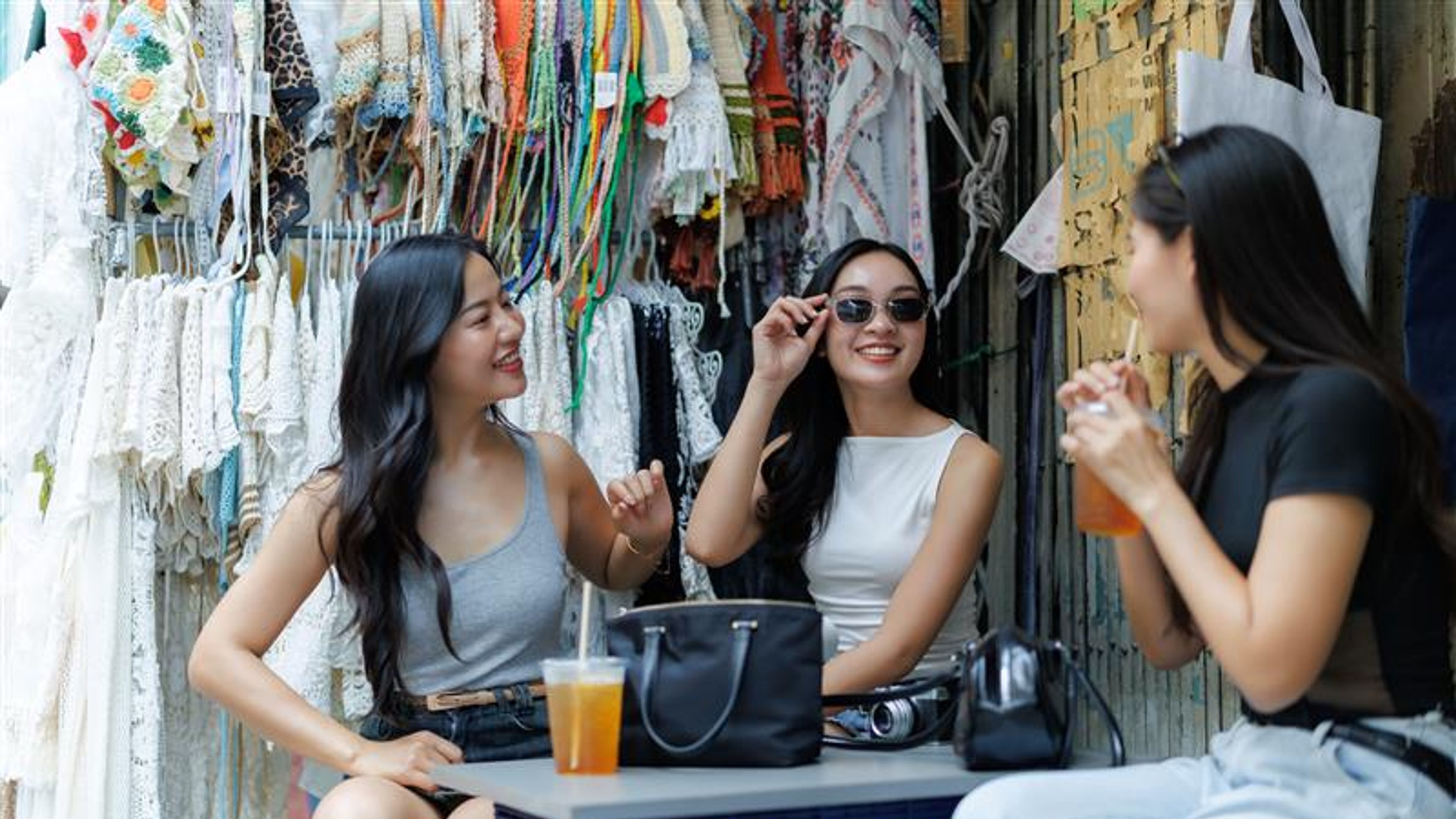 Young women talking and drinking juice at outdoor market